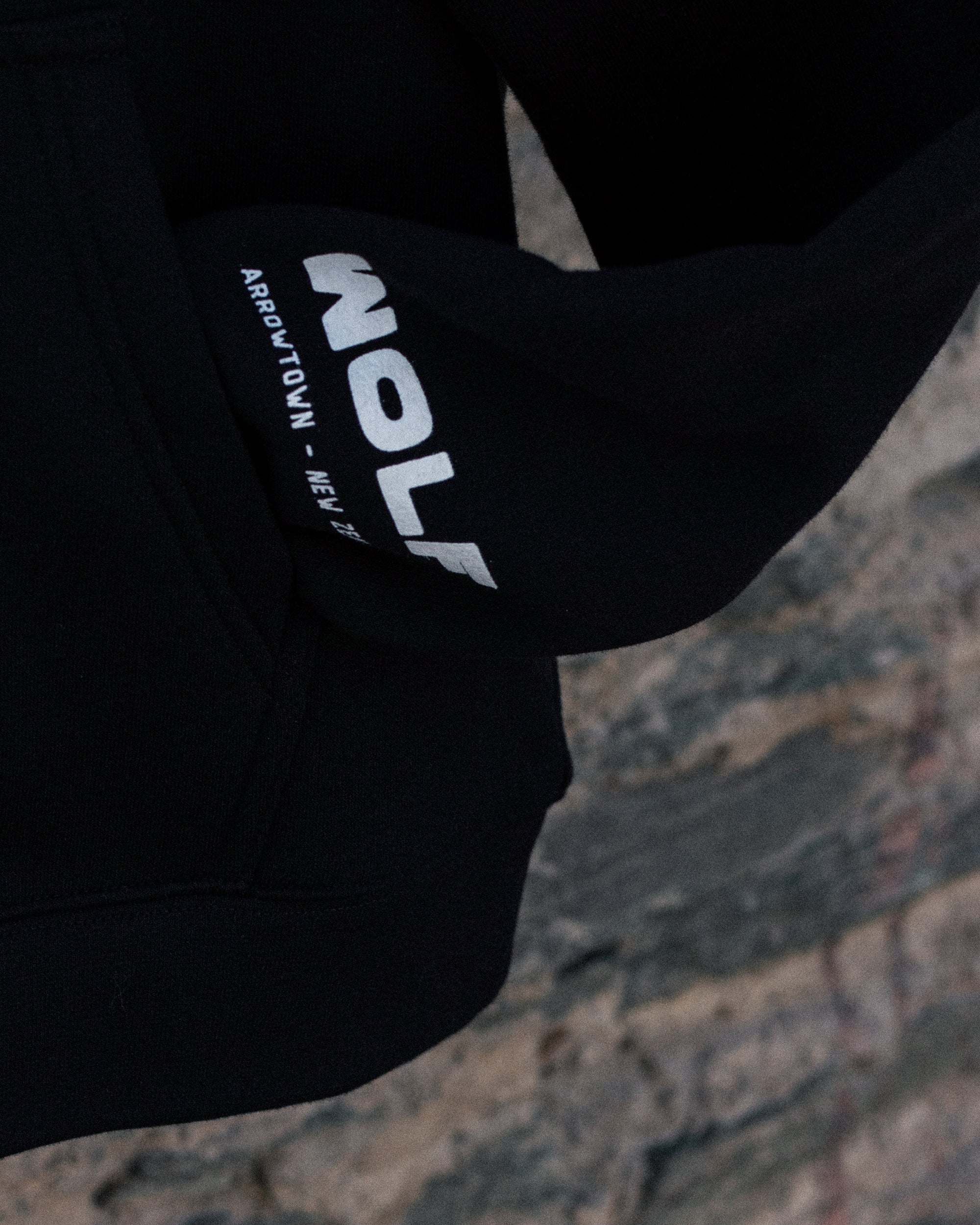 Close-up of a black sleeve with a brand logo on a textured surface