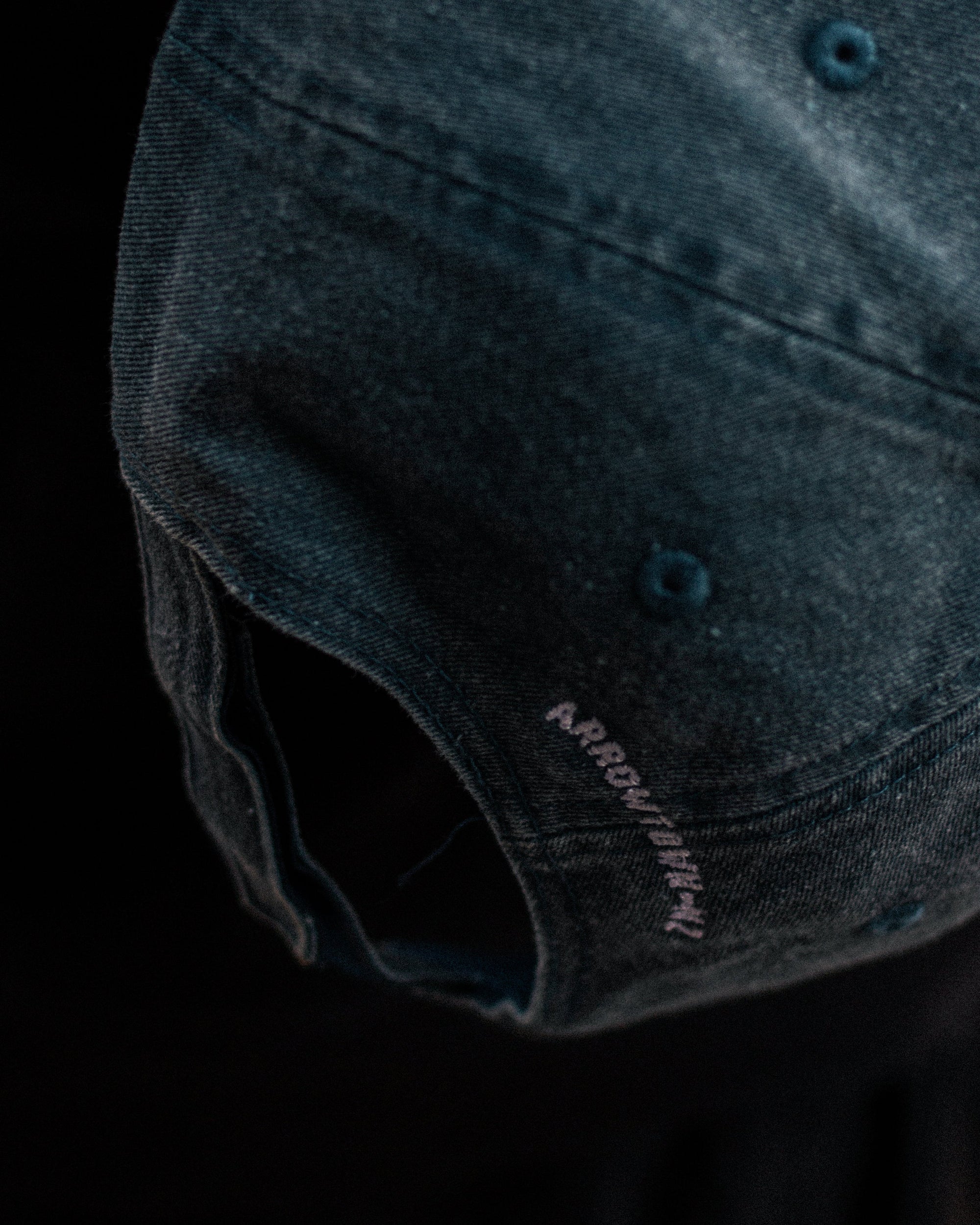 Dark denim cap with brand logo on a black background