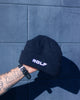 Navy beanie with 'WOLF' logo held against a blue tiled wall