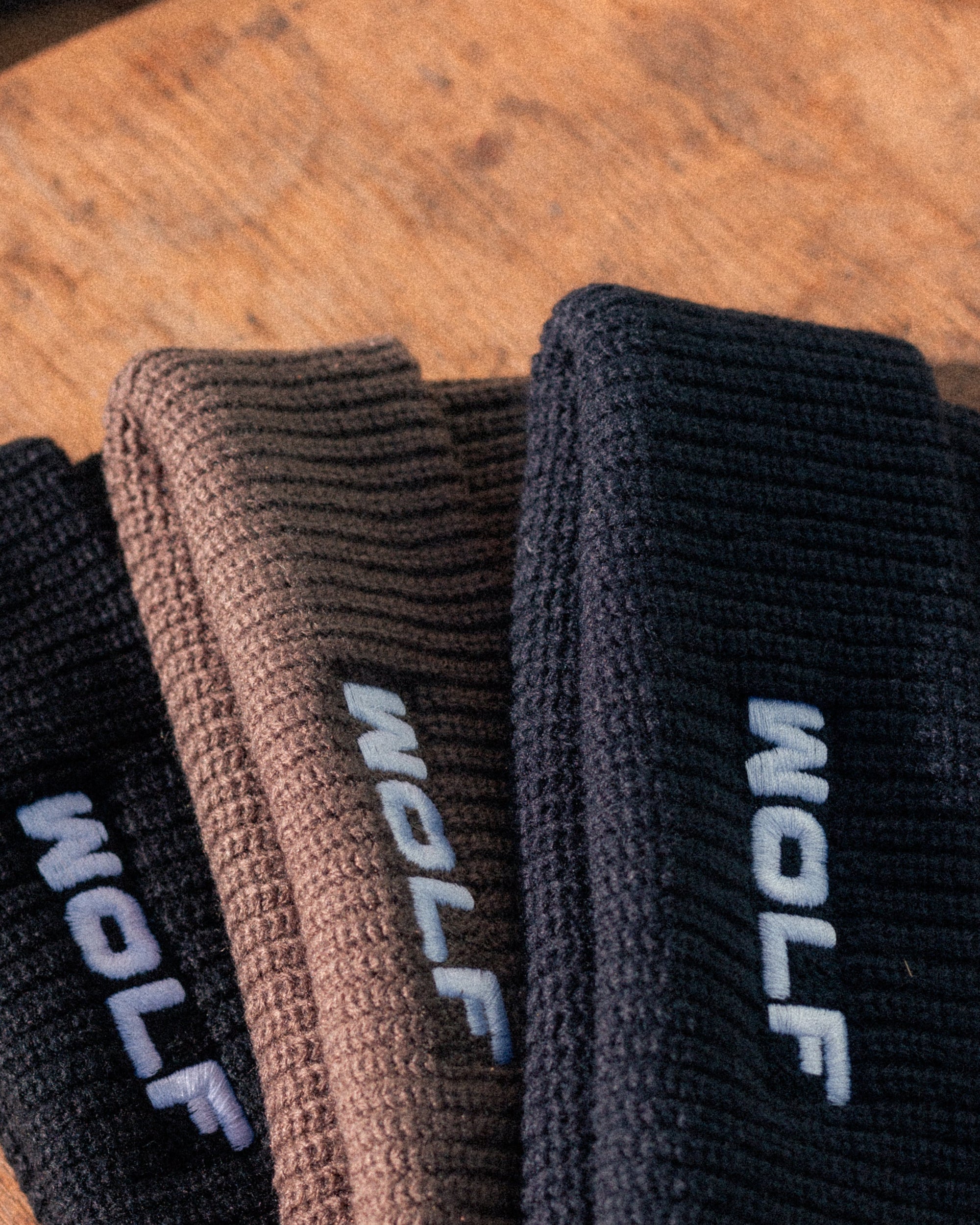 Three pairs of Beanies with 'WOLF' branding on a wooden surface