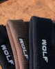 Three pairs of Beanies with 'WOLF' branding on a wooden surface